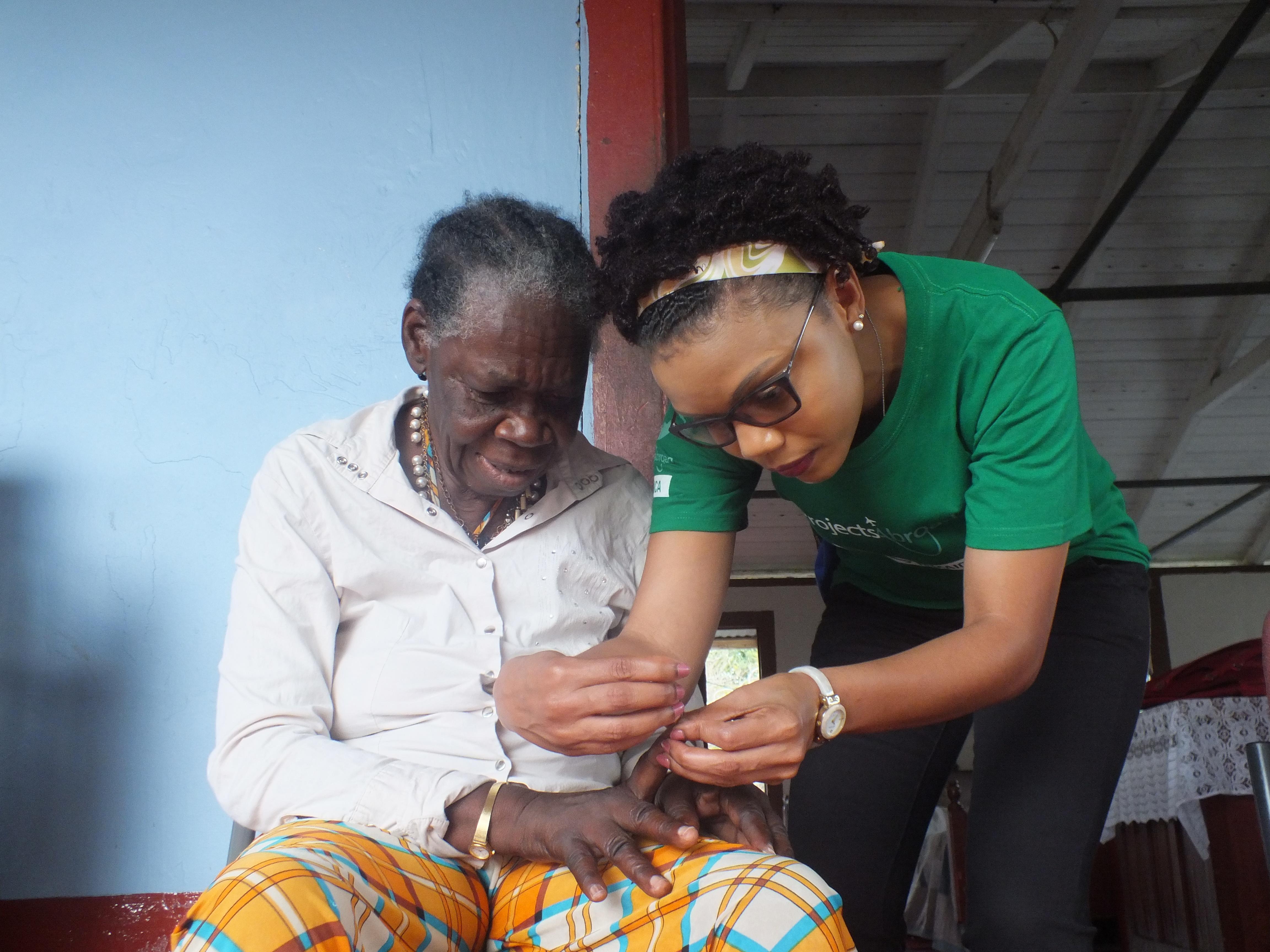 A Projects Abroad volunteer clips an elderly woman's nails during a community outreach in Jamaica. Projects Abroad volunteer helps an elderly woman with personal care during an outreach in Jamaica.